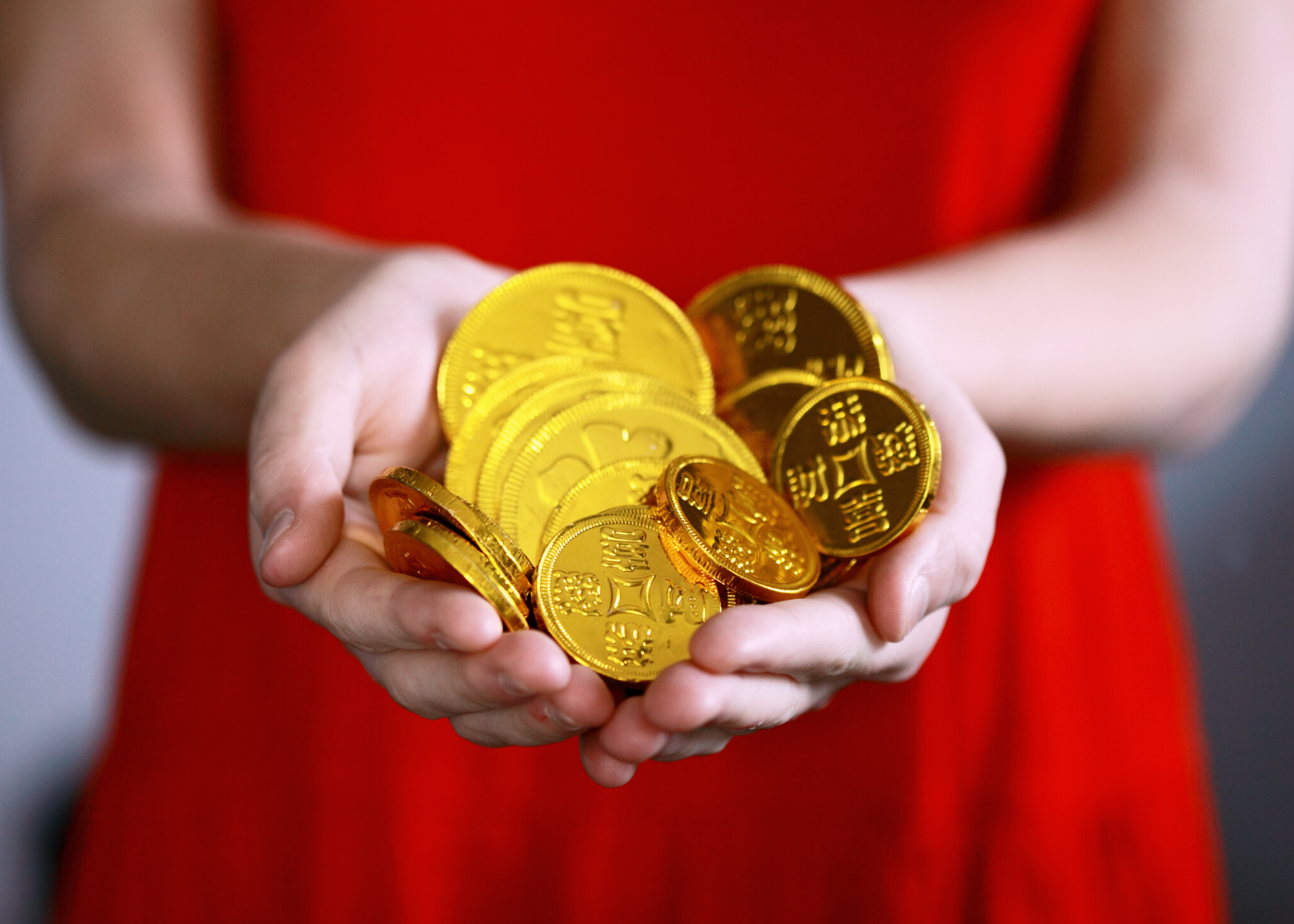 woman in red holding chocolate gold coins