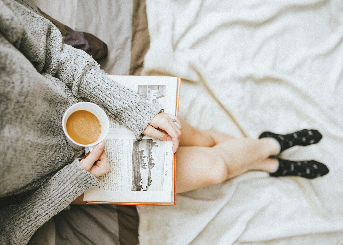 woman holding coffee and book